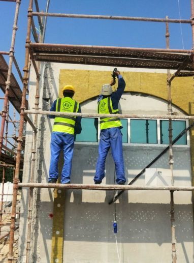 Two workers in yellow vests on scaffolding, using Steel Framing System (SFS)